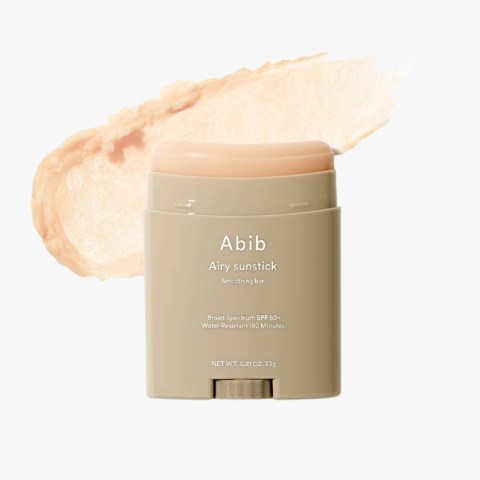Beige sunscreen stick labeled 'Abib Airy sunstick' with a peachy swatch behind it, a smoothing bar for SPF 50+ protection (80 minutes water resistant).
