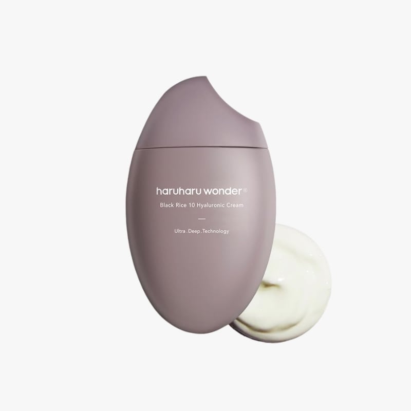 Purple oval skincare bottle labeled Haruharu Wonder Black Rice 10 Hyaluronic Cream, with cap off and cream swirled beside it.
