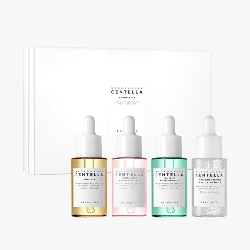 Four Centella ampoule bottles (amber, pink, teal, clear glitter) with droppers, in front of a white box.