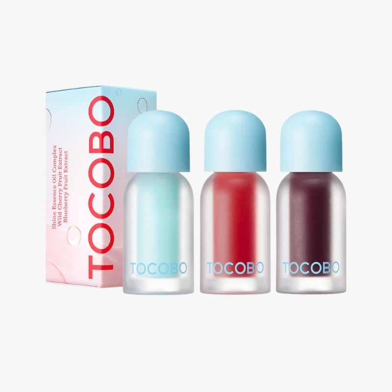Three TOCOBO cosmetic bottles with blue caps in pastel nail polish shades beside a pink TOCOBO box.