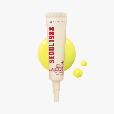 Beige cosmetic tube with red vertical text 'SEOUL 1988'—K-SECRET—standing upright, with bright yellow circles and droplets behind it.