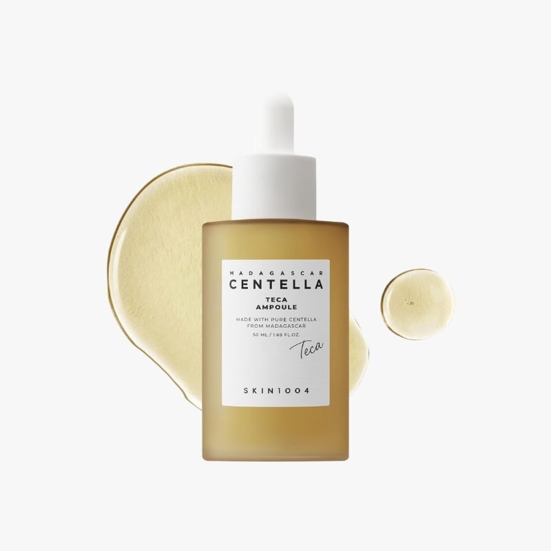 Skin1004 Madagascar Centella Teca Ampoule bottle with dropper, set against a gold-toned abstract background.