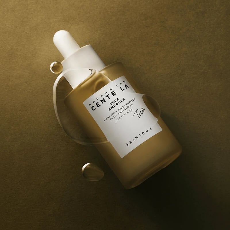 Brown glass dropper bottle of facial serum on a warm, gold-toned background.