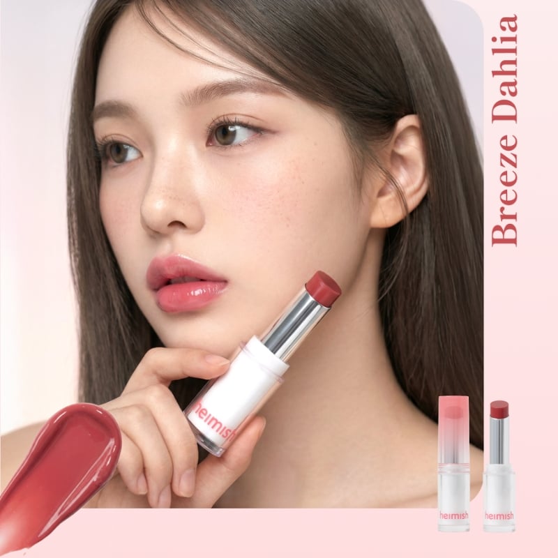 Close-up of a woman applying pink lipstick from a white tube; two lipstick tubes and a pink background with 'Breeze Dahlia' text visible on the side.