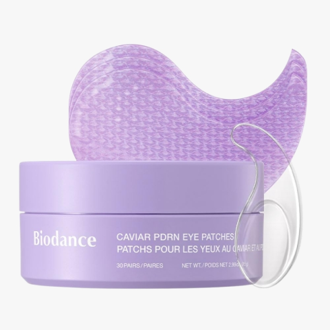 Lavender Biodance jar of caviar eye patches with a curved translucent patch behind it and a clear applicator/guide beside.