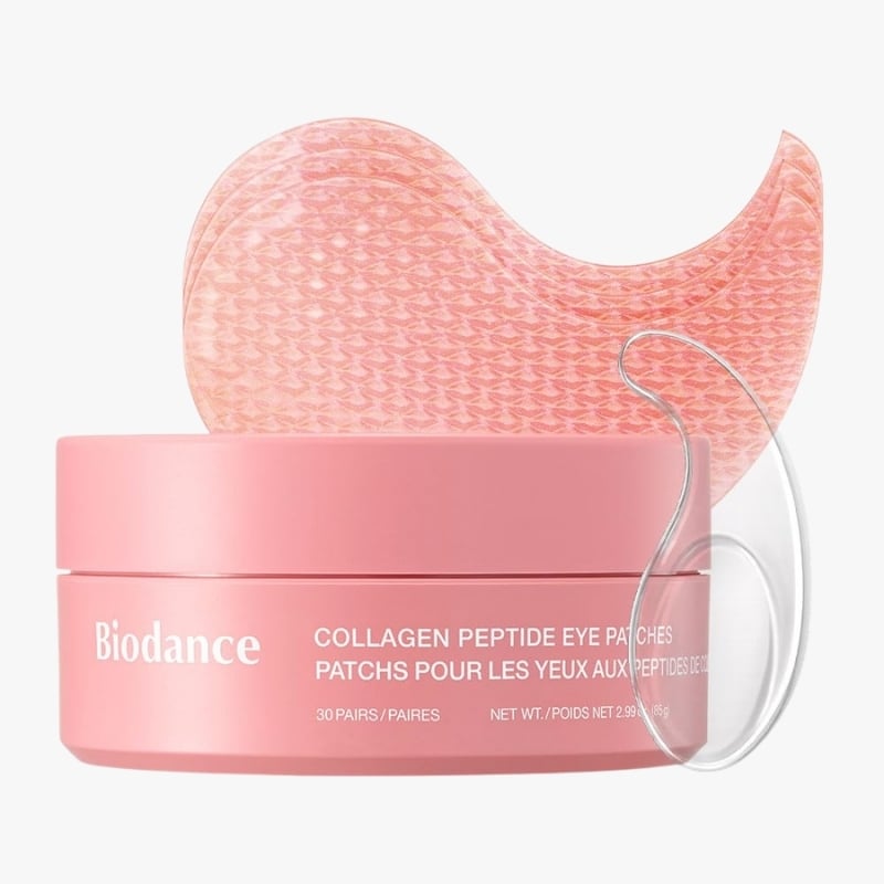Pink Biodance collagen peptide eye patches in a round pink jar with one patch resting on top.
