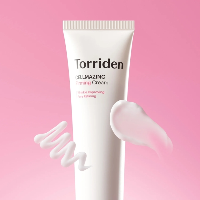 Tube of Torriden Cellmazing Firming Cream on a pink background with cream swirls illustrating texture, a cosmetic product.