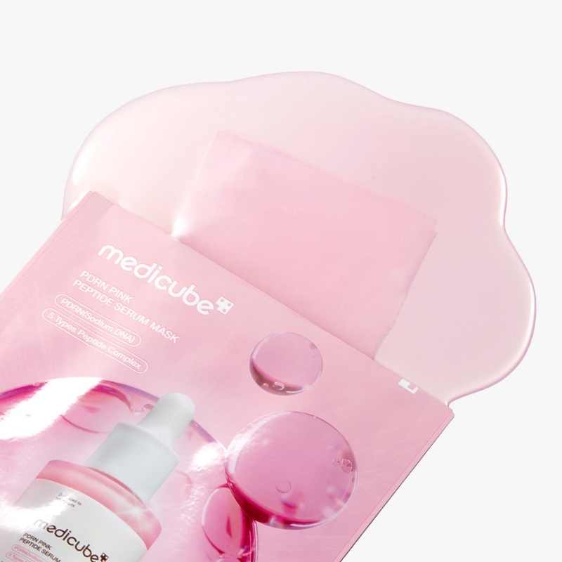 Pink Medicube facial sheet mask packet with serum liquid and a soft pink background
