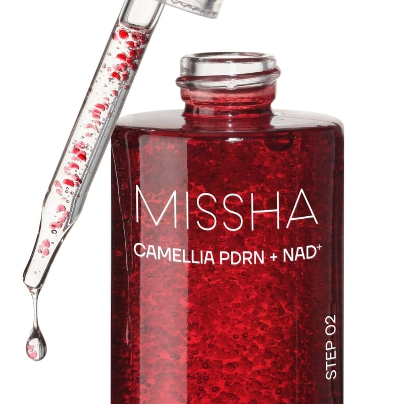 Close-up of a red Missha serum bottle (Camellia PDRN + NAD+) with a dropper, showing the liquid and bubbles inside the bottle.