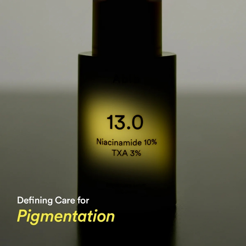 Bottle of skincare serum labeled '13.0' with Niacinamide 10% and TXA 3% and a glow around the text; caption reads 'Defining Care for Pigmentation'